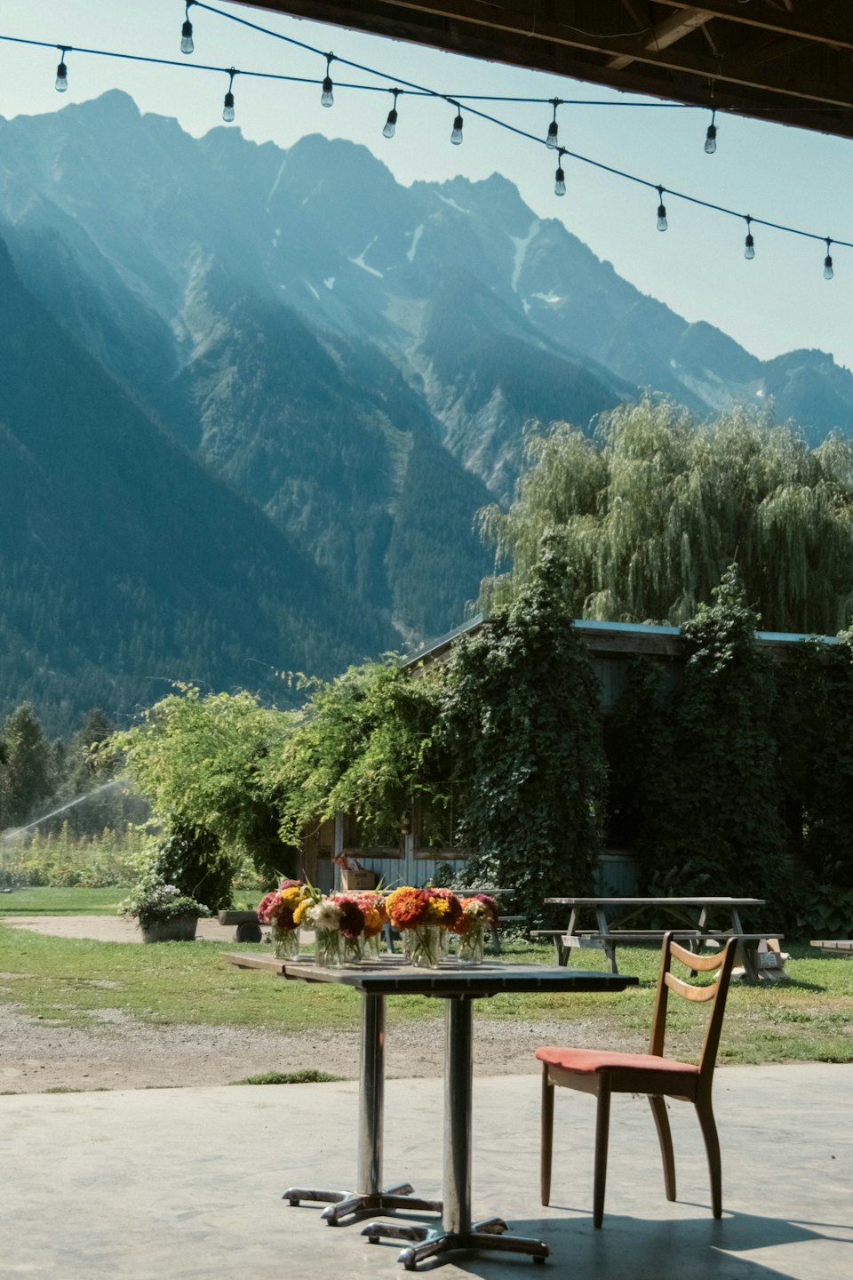 Flower bouquets sit on a patio table with mountains behind.