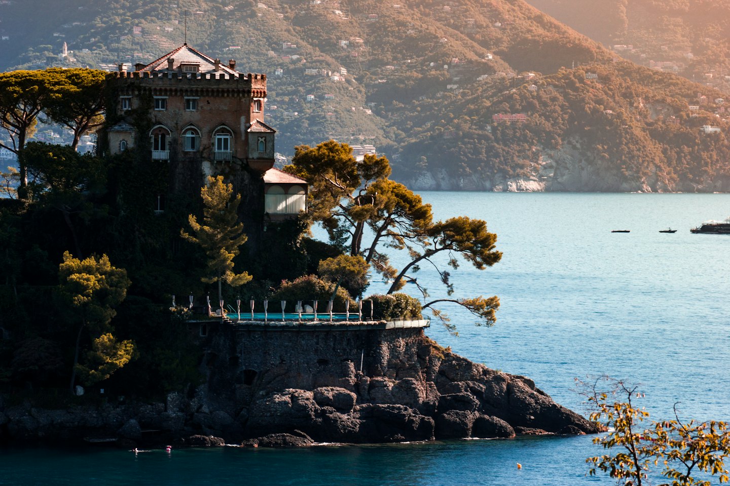 Villa on a cliff overlooking the sea with people swimming below.