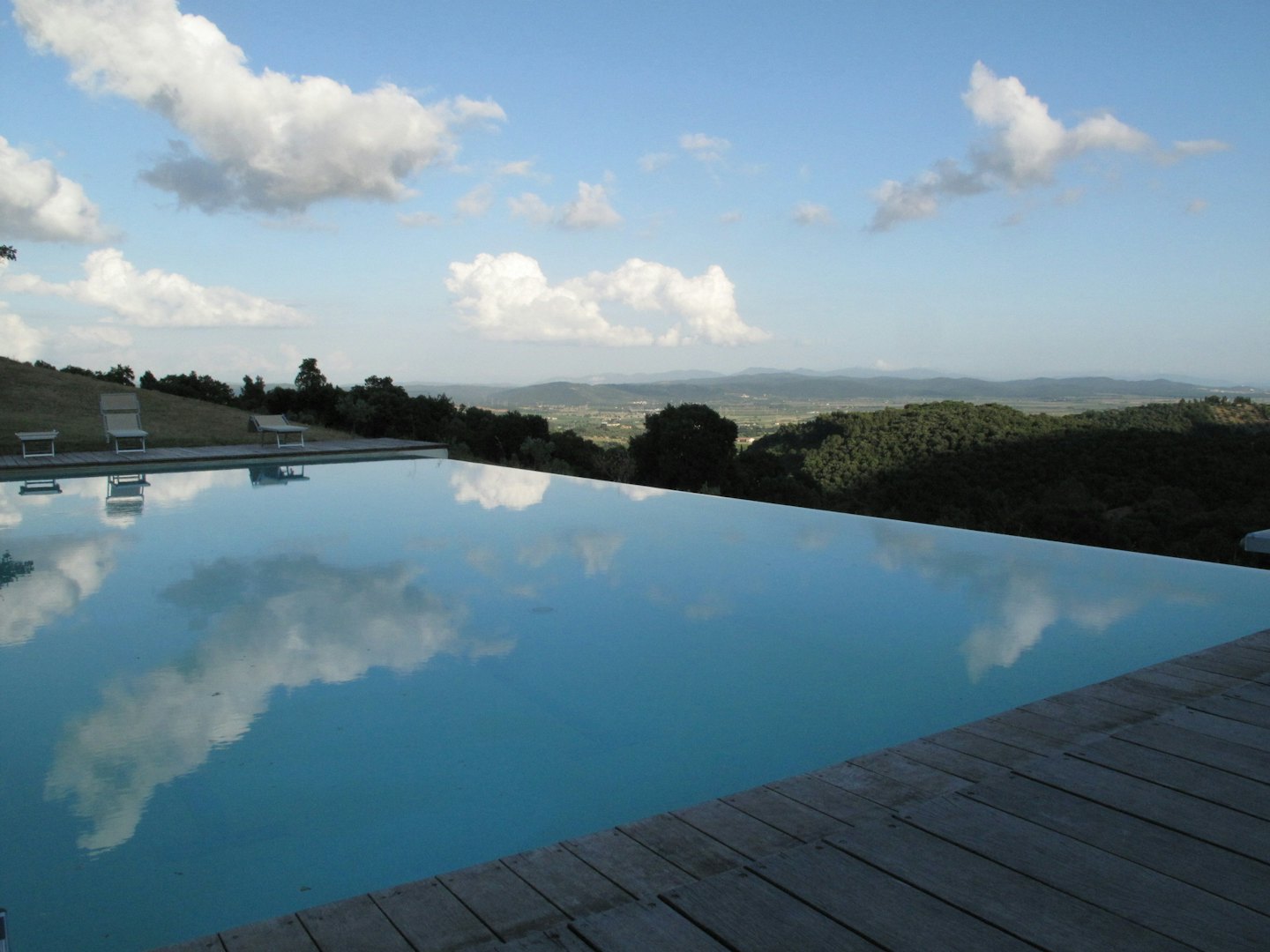 Infinity pool overlooking a valley and distant forested hills.