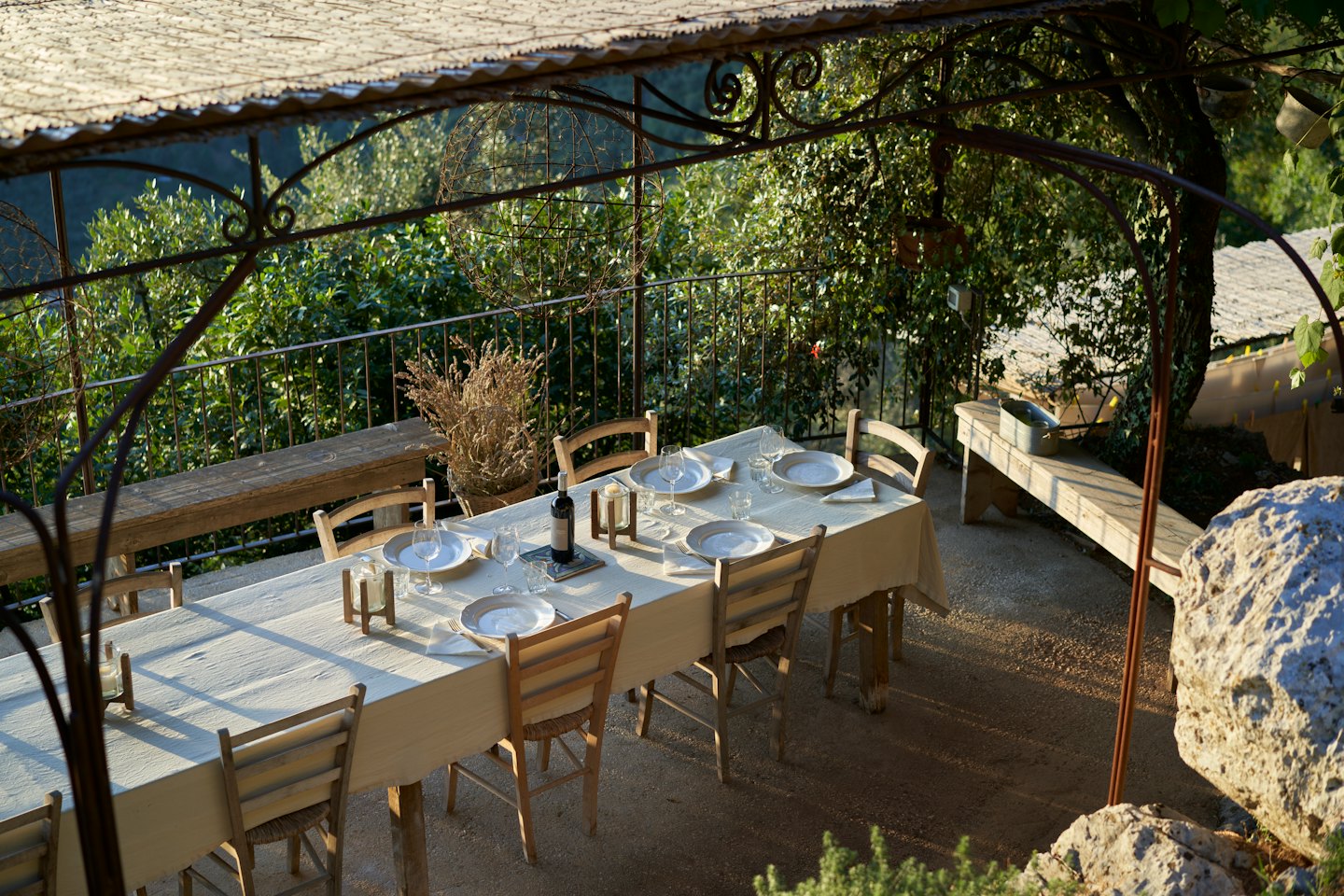 Outdoor dining table set for a meal on a stone patio.